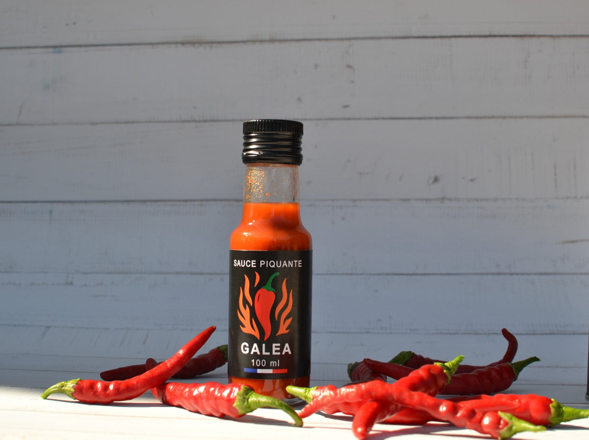 Flacon de sauce piquante GALEA entouré de piments rouges